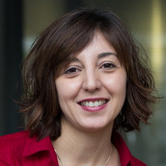 A woman with shoulder-length brown hair, smiling, wearing a red shirt.