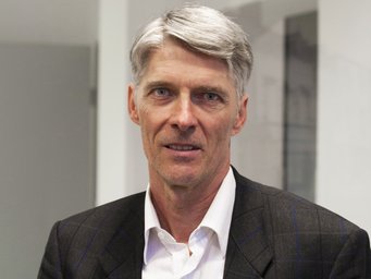 Mark Ebers has been a member of the IMPRS Faculty since 2007 A man with gray hair, wearing a dark blazer over a white shirt, is looking directly at the camera.