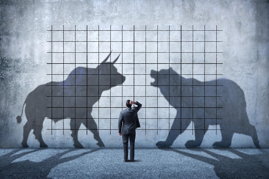 Businessman observes shadows of bull and bear on a grid-marked concrete wall.