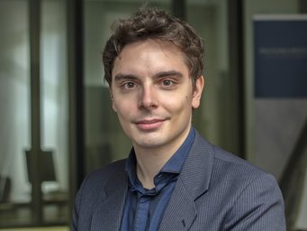 Person in a striped suit, background with glass wall and poster.