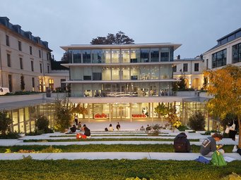 Sciences Po, 1 Saint Thomas campus Contemporary academic building with glass walls, illuminated interior, and landscaped outdoor seating, students studying outside.