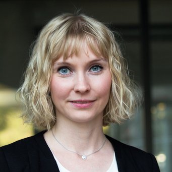 © MPIfG / Dünkelmann A woman with blonde, curly hair, wearing a black blazer, looks directly at the camera.