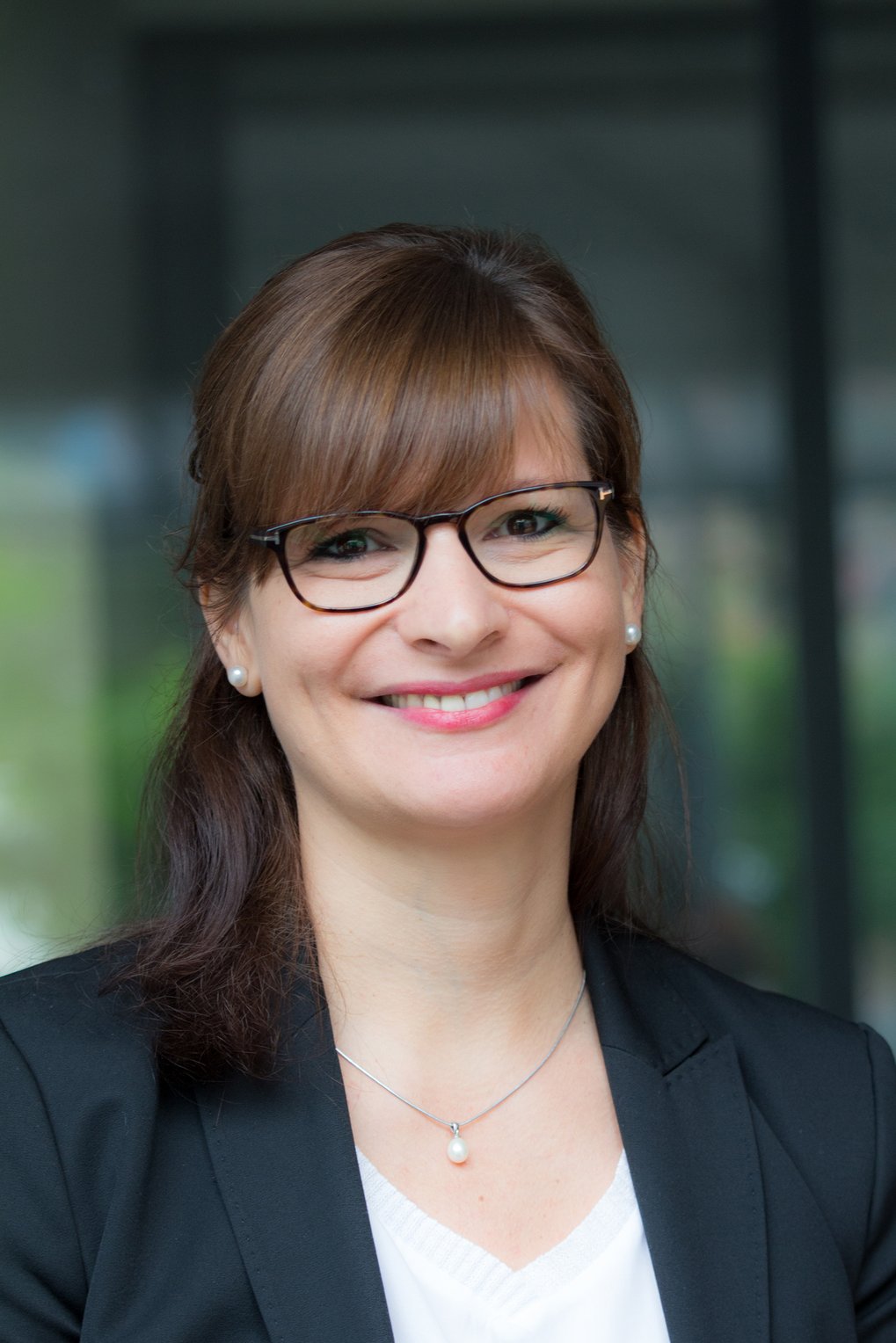 A smiling woman with glasses and brown hair, wearing a black blazer.