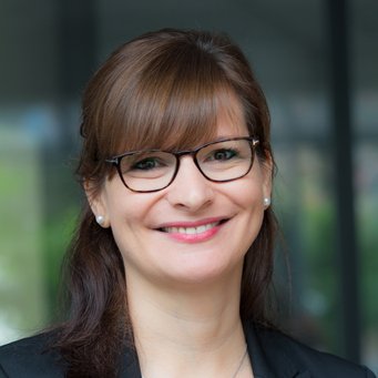 © MPIfG / Dünkelmann A smiling woman with glasses and brown hair, wearing a black blazer.
