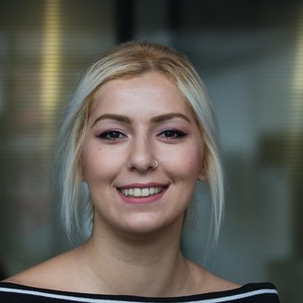 © MPIfG / Dünkelmann A young woman with light blonde hair, smiling, wearing a black and white striped top.