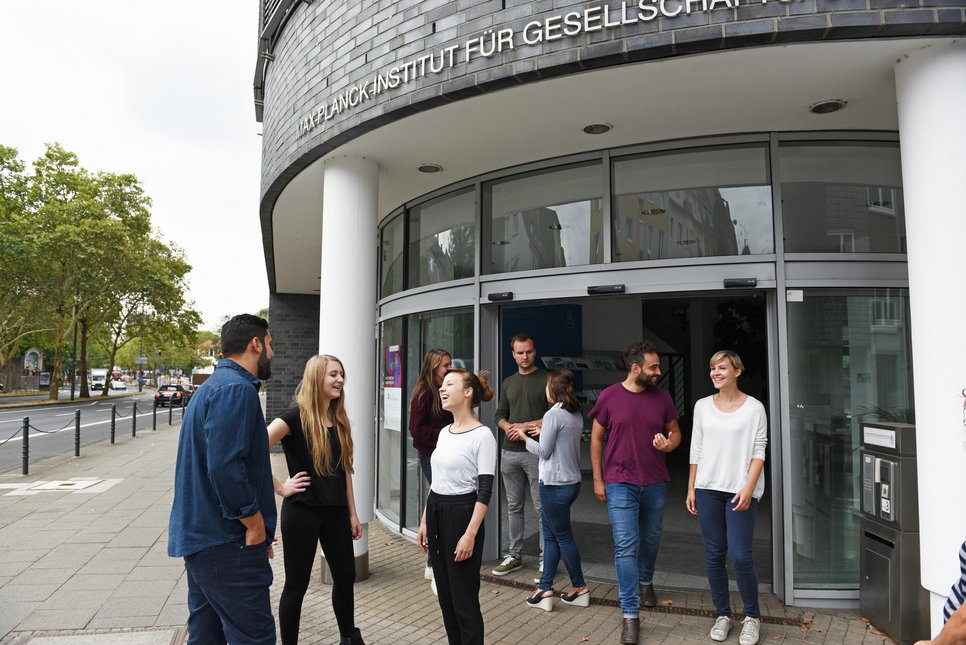 A group of people socializing outside a building with a sign that reads "WZB Wissenschaftszentrum Berlin für Sozialforschung."