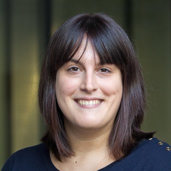 A smiling woman with shoulder-length dark brown hair, wearing a navy blue top, poses for a photo.
