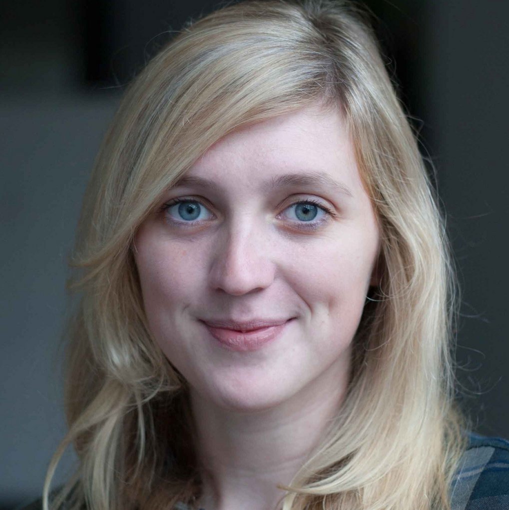 A blonde woman with blue eyes is smiling at the camera.