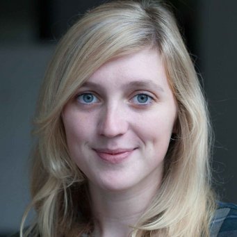A blonde woman with blue eyes is smiling at the camera.
